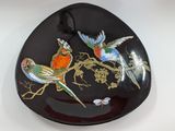a black plate with birds painted on it on a table
