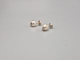une paire de boucles d'oreilles à clous en perles posée sur une surface blanche