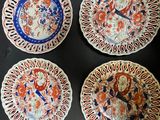 four plates with designs on them sitting on a table
