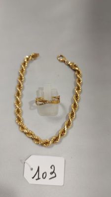 un gros plan d'un bracelet et d'une bague en or posés sur une surface blanche