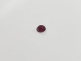 a single red garnet stone sitting on top of a white surface