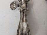 a silver vase on the wall next to a knife