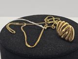 un gros plan sur une boîte noire sur laquelle est posé un collier en or