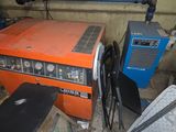 an orange and black machine sitting in a room next to a pile of junk