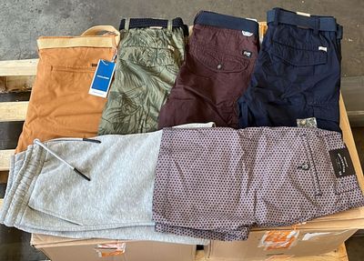 plusieurs paires de pantalons pour homme posées sur une caisse en bois