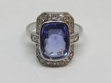 gros plan d'une bague avec une pierre bleue entourée de diamants