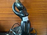 une statue représentant une femme tenant une lampe posée sur une table