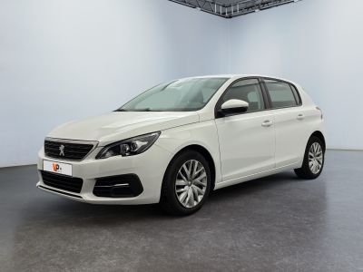 La voiture blanche est garée dans une grande pièce au sol noir.
