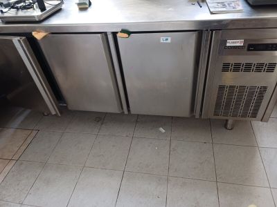 un plan de travail en inox équipé de deux réfrigérateurs et d'une cuisinière