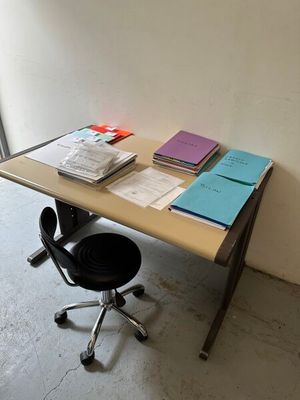 un bureau avec des livres et une chaise devant une fenêtre