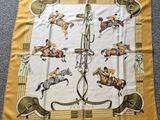 écharpe jaune avec des chevaux et des jockeys dessinés sur un tapis