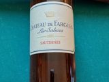 une bouteille de vin posée sur une table de billard, à côté d'une queue de billard