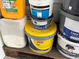 several buckets of paint are stacked on a pallet in a garage