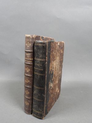 two old books sitting on top of each other on a table