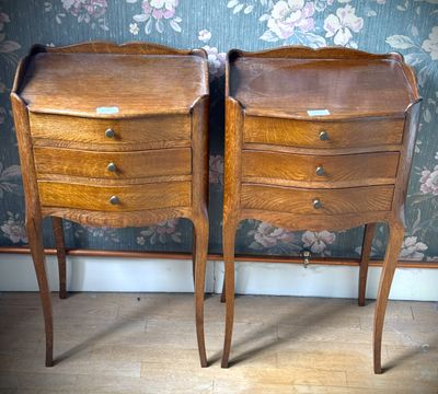 deux tables en bois munies de tiroirs, placées devant un mur recouvert d'un papier peint à motifs floraux