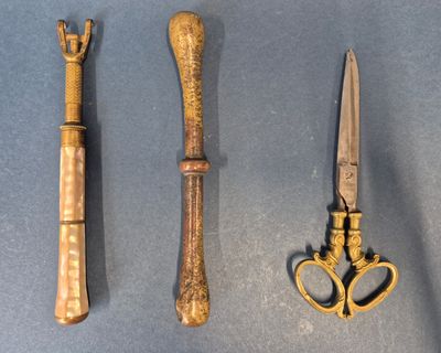 trois types de couteaux différents et une paire de ciseaux posés sur une table
