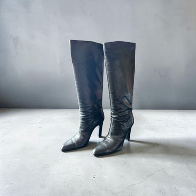 une paire de bottes en cuir noir à talons hauts posées sur un sol en béton