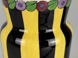 yellow and black striped vase with purple flowers on the rim