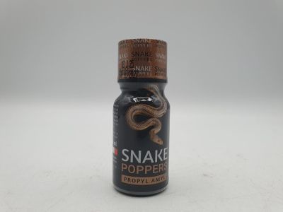 un gros plan d'une bouteille de piment « snake pepper » posée sur une surface blanche
