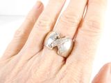 a woman ' s hand holding a ring with an elephant on it