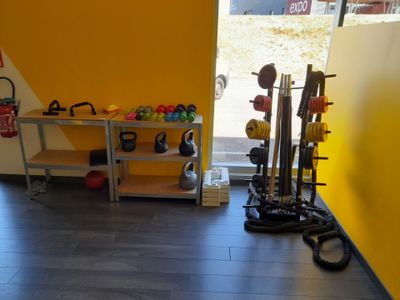 une pièce avec un mur jaune et un support sur lequel sont posés des kettlebells