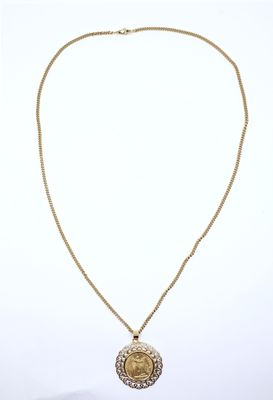 a gold necklace with a coin and a chain on a white background