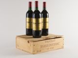 three bottles of red wine in a wooden crate on a white background