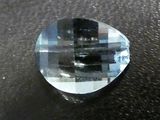 an image of a faceted blue topazte stone on a black surface