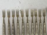 six forks, a spoon and a spoon rest on a table