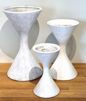 three white vases sitting on a table next to each other