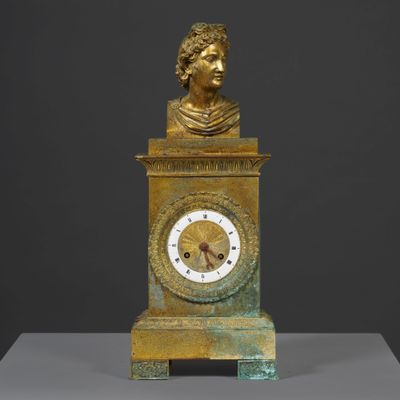 a gold clock with a bust on top of it
