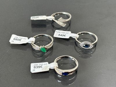 quatre bagues différentes, munies d'étiquettes, posées sur une table