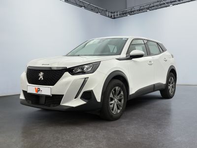 Une voiture blanche est garée dans une grande pièce au sol noir.