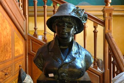 une statue représentant une femme coiffée d'un chapeau, sur les marches