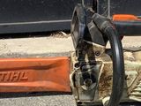 une tronçonneuse posée par terre à côté d'un objet orange