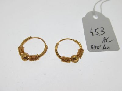 deux boucles d'oreilles en anneau dorées avec une étiquette de prix sur un fond blanc