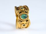 une image d'un gros plan d'une bague en or avec une pierre verte
