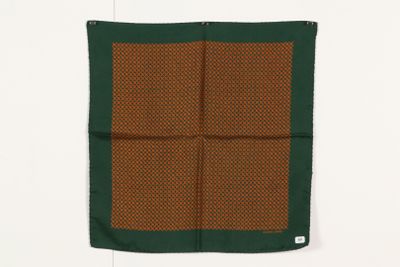une écharpe carrée marron et verte accrochée à un mur blanc