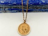 un collier avec une pièce d'or posée sur une pierre bleue
