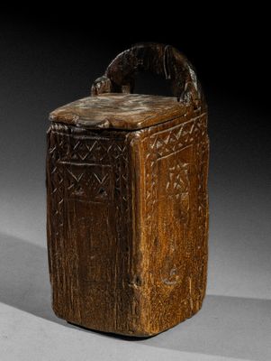 une vieille boîte en bois munie d'une poignée, sur un fond gris