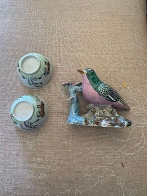 un petit oiseau perché sur une assiette, à côté de deux tasses