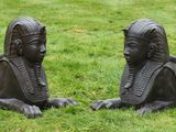 two statues of a man and a woman laying in the grass