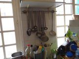 Dans une cuisine, des casseroles et des poêles sont accrochées au mur