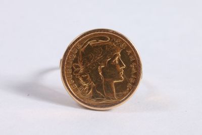 un gros plan d'une bague en forme de pièce de monnaie sur laquelle est représenté le visage d'une femme
