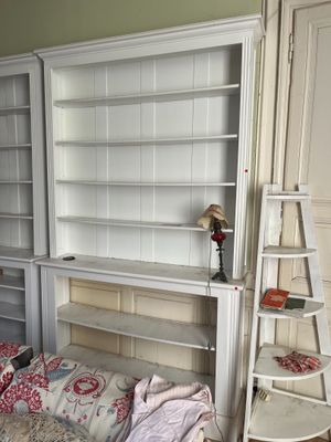 a white bookcase with a ladder next to a bed