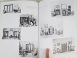 a person holding a book open to show pictures of a living room