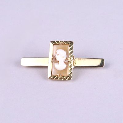 a close up of a gold tie bar with a picture of a woman on it