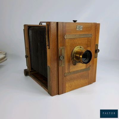 un vieil appareil photo en bois posé sur une surface blanche