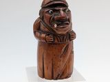 an old wooden statue of a man with a hat and a cane