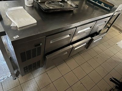 stainless steel counter top in a commercial kitchen with oven and dishwasher